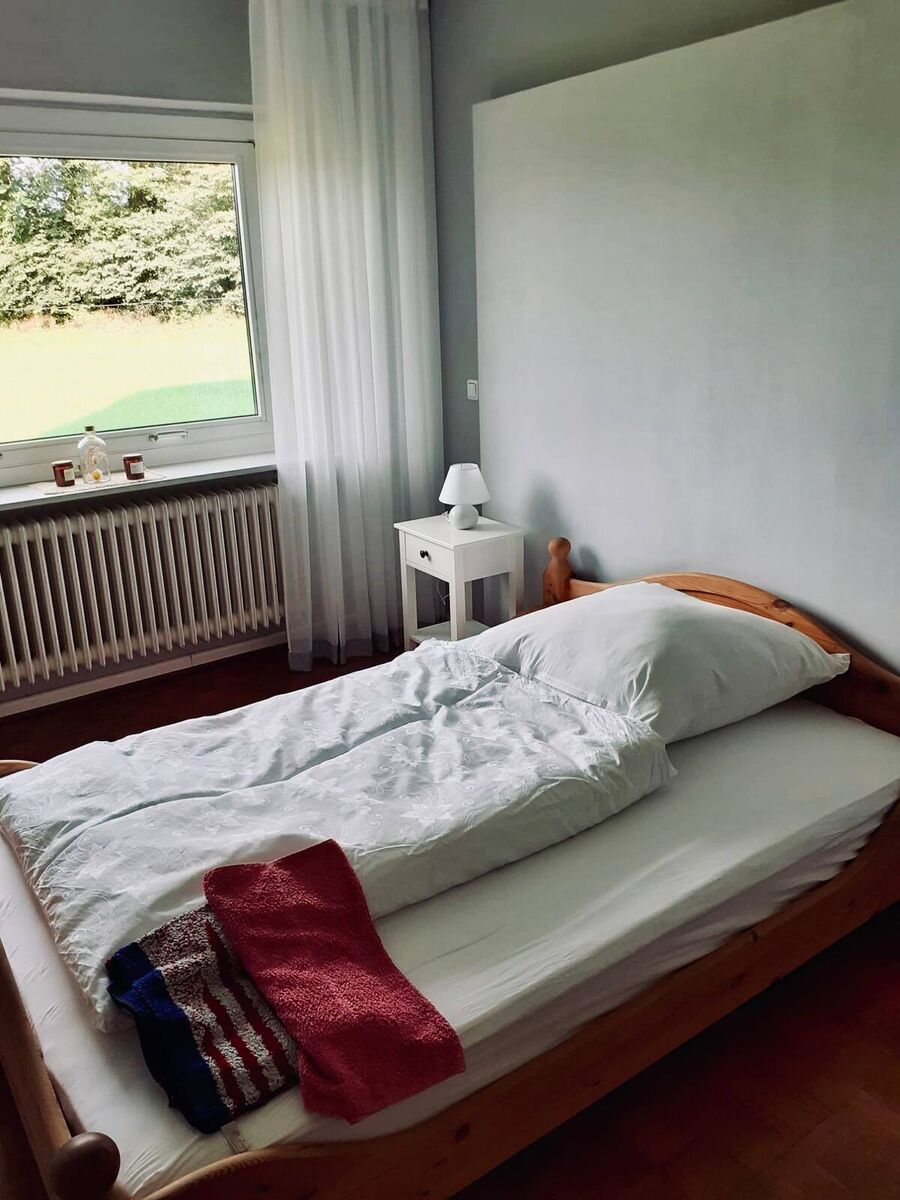 Mehrbettzimmer – zwei Einzelbetten mit Sitzecke Geräumiges Zimmer mit zwei Einzelbetten, Sessel und Teppich im Haus Wiesenblick Vaale