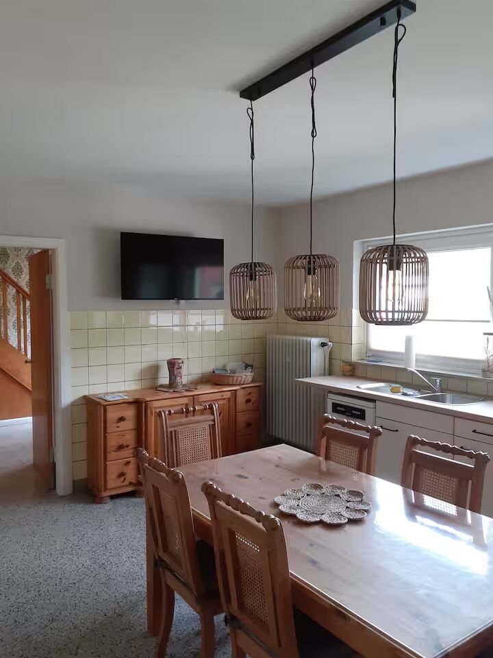 Wohnküche mit Essbereich – Haus Wiesenblick Gemütliche Wohnküche mit Holztisch, Rattanlampen und TV im Haus Wiesenblick Vaale
